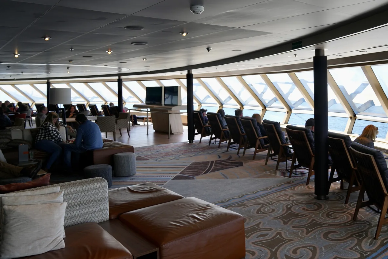 Passengers talking and relaxing in the observation lounge aboard Nieuw Amsterdam