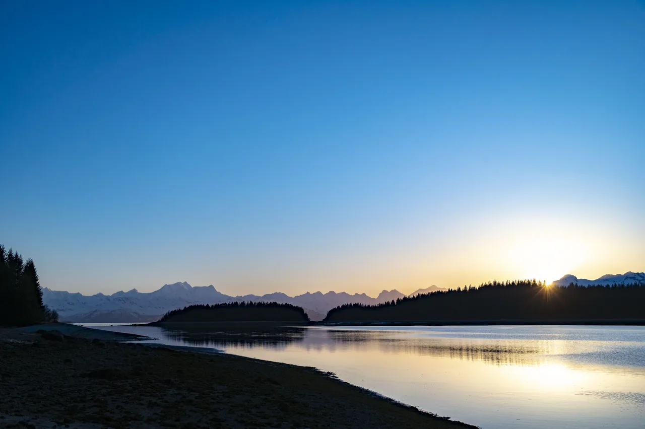Evening light over a quiet shoreline at South Sandy Cove with the Fairweather Range on the horizon in Glacier Bay, Alaska