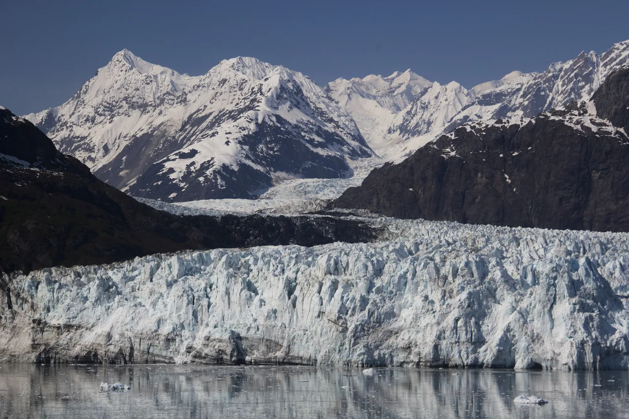 The blue-white ice face of Margerie Glacier below the snow-covered Fairweather Range in Glacier Bay, Alaska
