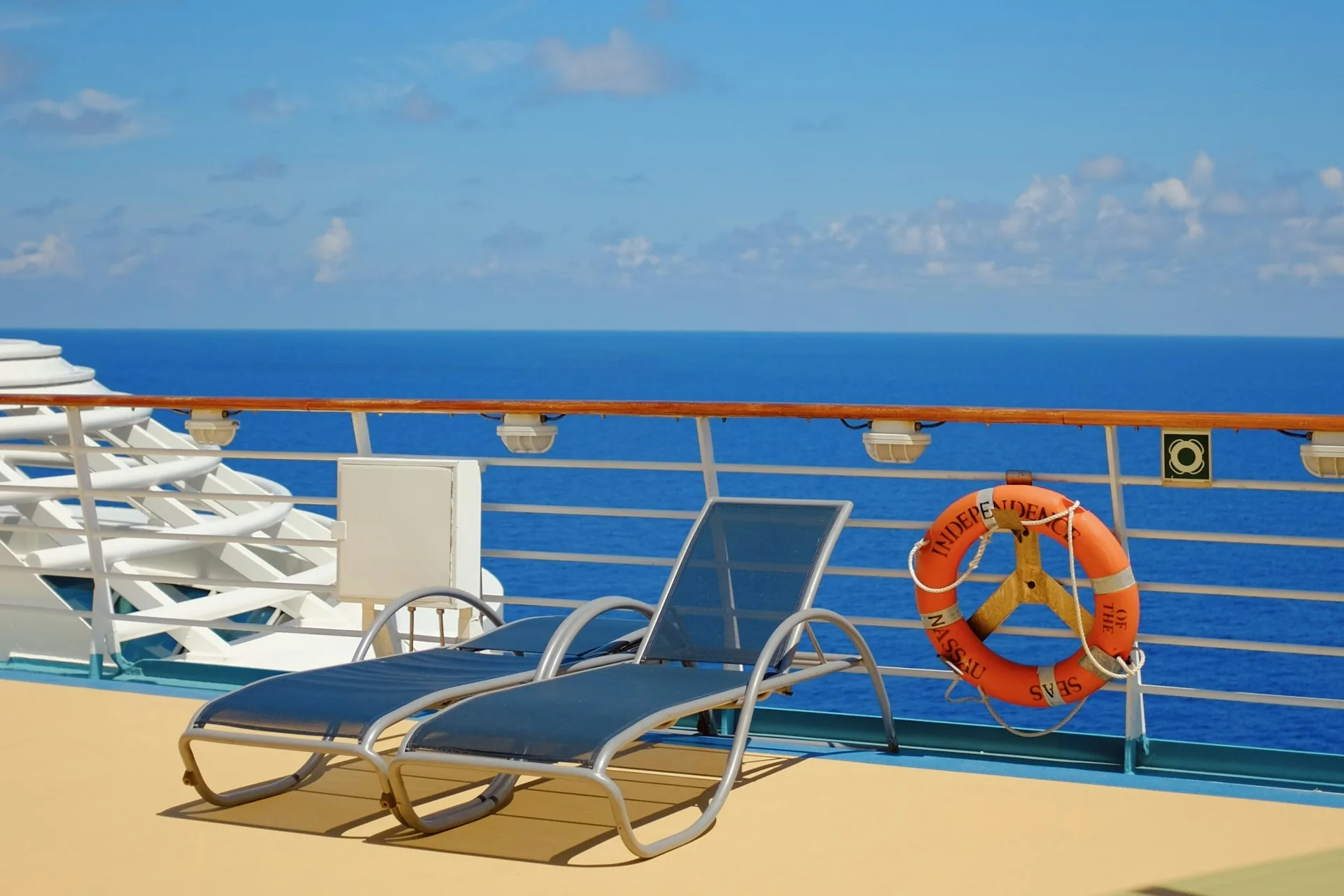 Lounge chairs on an open cruise ship deck overlooking the ocean